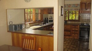 A kitchen with wooden cabinets, a sink, a stove, and a clock on the wall. - Mansfield House - Country Holiday Accommodation, Sleeps 10, up to 15 (Mansfield)
