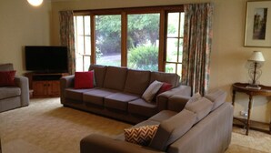 A living room with a sectional sofa, a television, and a lamp. - Mansfield House - Country Holiday Accommodation, Sleeps 10, up to 15 (Mansfield)