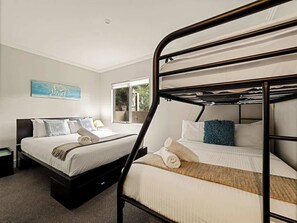 A hotel room with two bunk beds, a large window, and a painting on the wall.