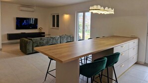 Een moderne keuken met een houten kookeiland, barstoelen en een televisie in de woonruimte.
