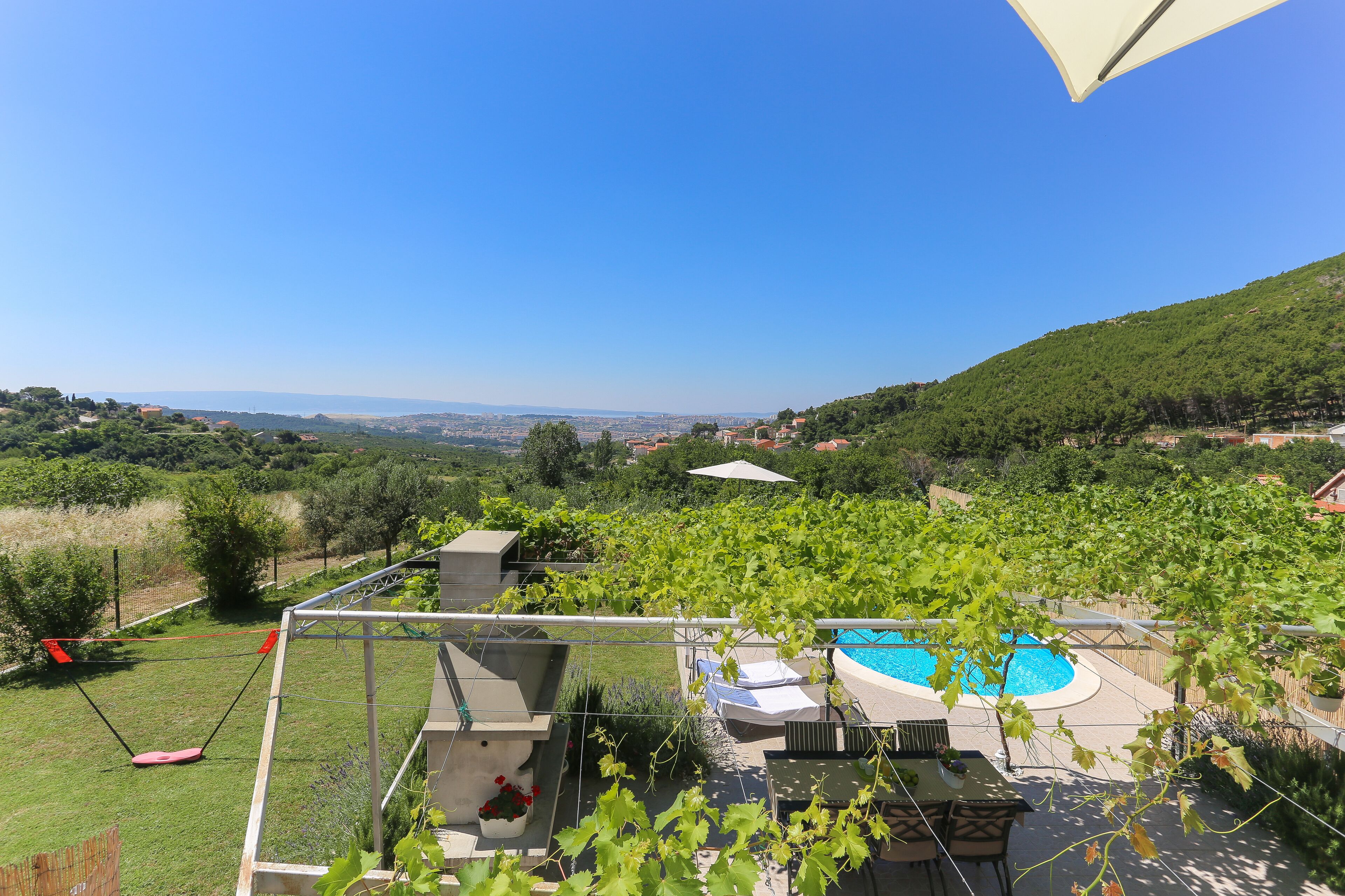 Une terrasse sur le toit avec une piscine, des espaces de détente en plein air et une vue sur la campagne.