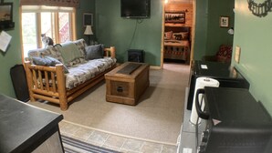 A living room with a sofa, a wooden coffee table, a television, and a fireplace.
