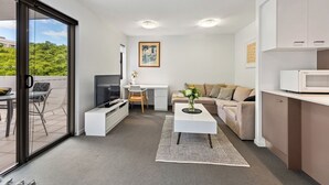 A compact living space with a balcony, a kitchenette, a sofa, a coffee table, and a TV. - Accommodation South Bank Brisbane 25meters from  Exhibition & Convention Centre  (South Brisbane)