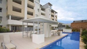 A modern hotel with a swimming pool, outdoor seating, and a covered patio area. - Accommodation South Bank Brisbane 25meters from  Exhibition & Convention Centre  (South Brisbane)