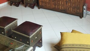 A living room with a red wall, a wooden cabinet with a flat-screen TV, and decorative items. - A Cozy Flat In A Quite Neighborhood (Fès)