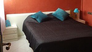 A bedroom with a bed, a nightstand, a lamp, and a wall-mounted air conditioner. - A Cozy Flat In A Quite Neighborhood (Fès)
