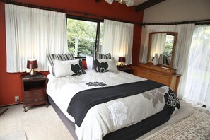 A bedroom with a large bed, two bedside tables, a dresser, and a mirror. - Rose Lake Retreat - Spa Pool, Lake Views, Sleeps 8 (Rotorua)