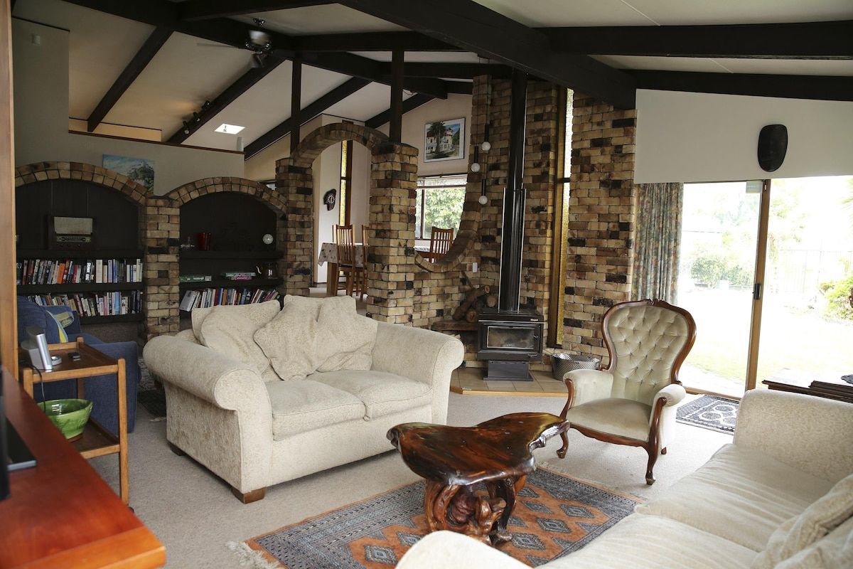 A cozy living room with a fireplace, a sofa, a chair, and a bookshelf.