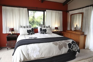 A bedroom with a large bed, two bedside tables, a dresser, and a mirror.