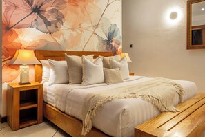 Cama bem arrumada com cabeceira de madeira, luminária de cabeceira e mesa de cabeceira de madeira.