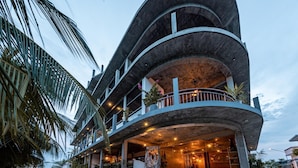 A multi-story hotel with a curved facade, outdoor seating area, and palm trees. - Club Gabbiano Rasdhoo (Rasdhoo)