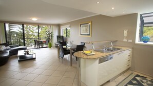 A modern apartment with a kitchen, dining area, and living room. - Oceanview 6 at Nambucca with rooftop tce & spa (Nambucca Heads)