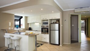 A modern kitchen with white cabinets, a built-in oven, a microwave, and a stainless steel refrigerator. - Oceanview 6 at Nambucca with rooftop tce & spa (Nambucca Heads)