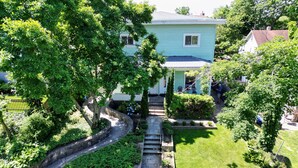 A light blue house with a stone staircase leading to a front door, surrounded by lush greenery and a well-maintained lawn. - Charming duplex with private yard. Close to the beach, dining & shopping! (Greenwich)
