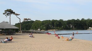 A beach with people relaxing on the sand, a pier, and a lake in the background. - Charming duplex with private yard. Close to the beach, dining & shopping! (Greenwich)