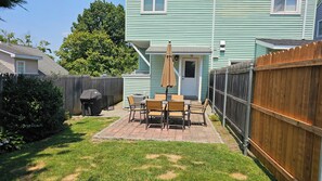 A backyard with a patio, a barbecue grill, and a wooden fence. - Charming duplex with private yard. Close to the beach, dining & shopping! (Greenwich)