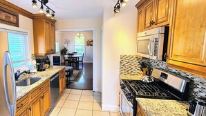 A kitchen with granite countertops, wooden cabinets, a stainless steel stove, and a microwave. - Charming duplex with private yard. Close to the beach, dining & shopping! (Greenwich)