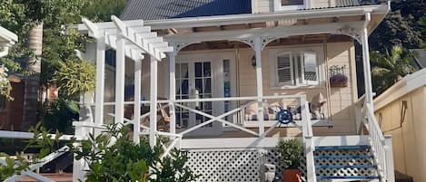 A two-story house with a porch, a small garden, and a white fence.