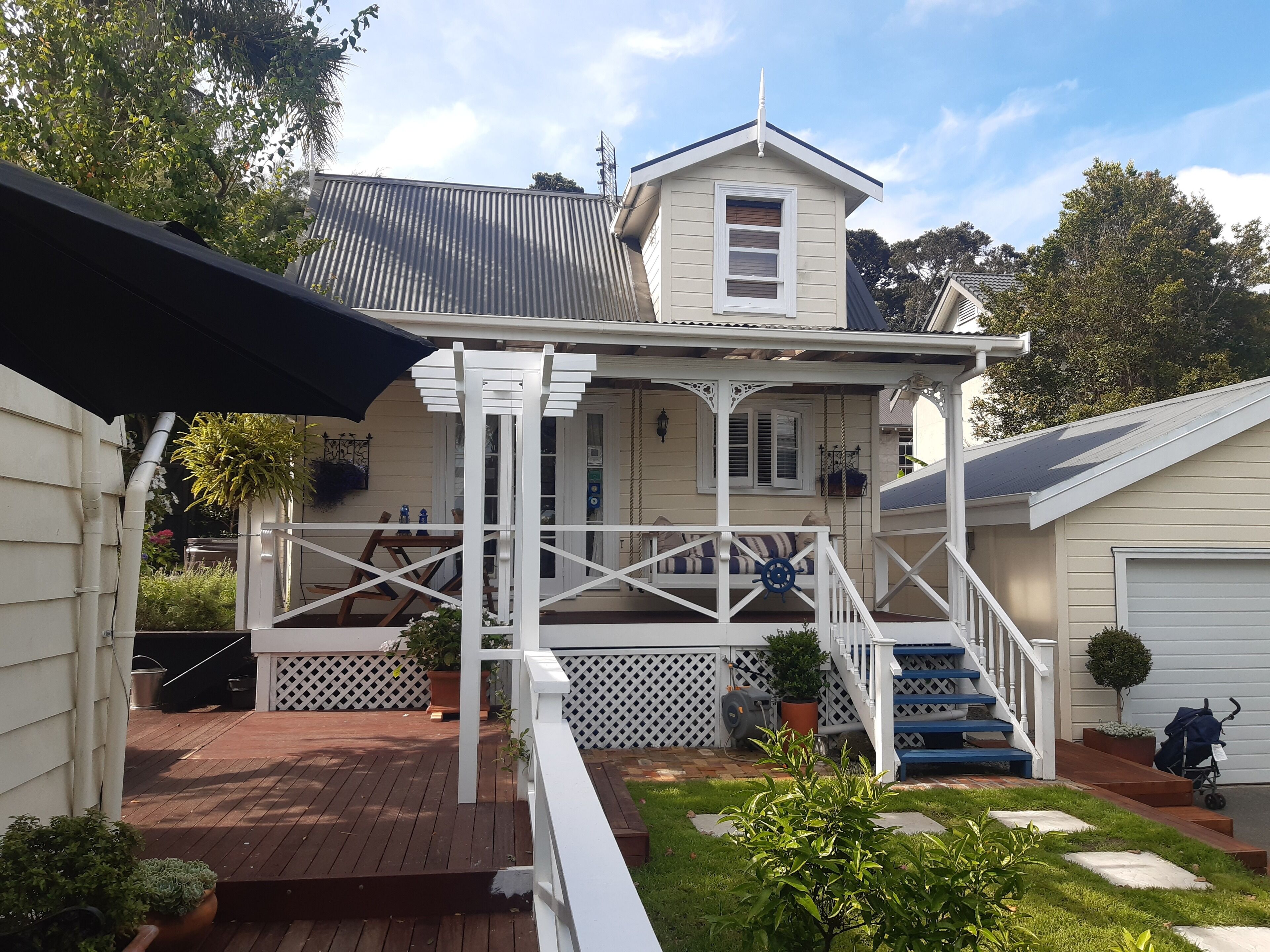 A two-story house with a porch, a staircase, and a small garden area.