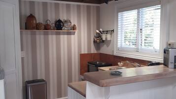 A kitchen with a central island, a window with blinds, a trash bin, and a sink.