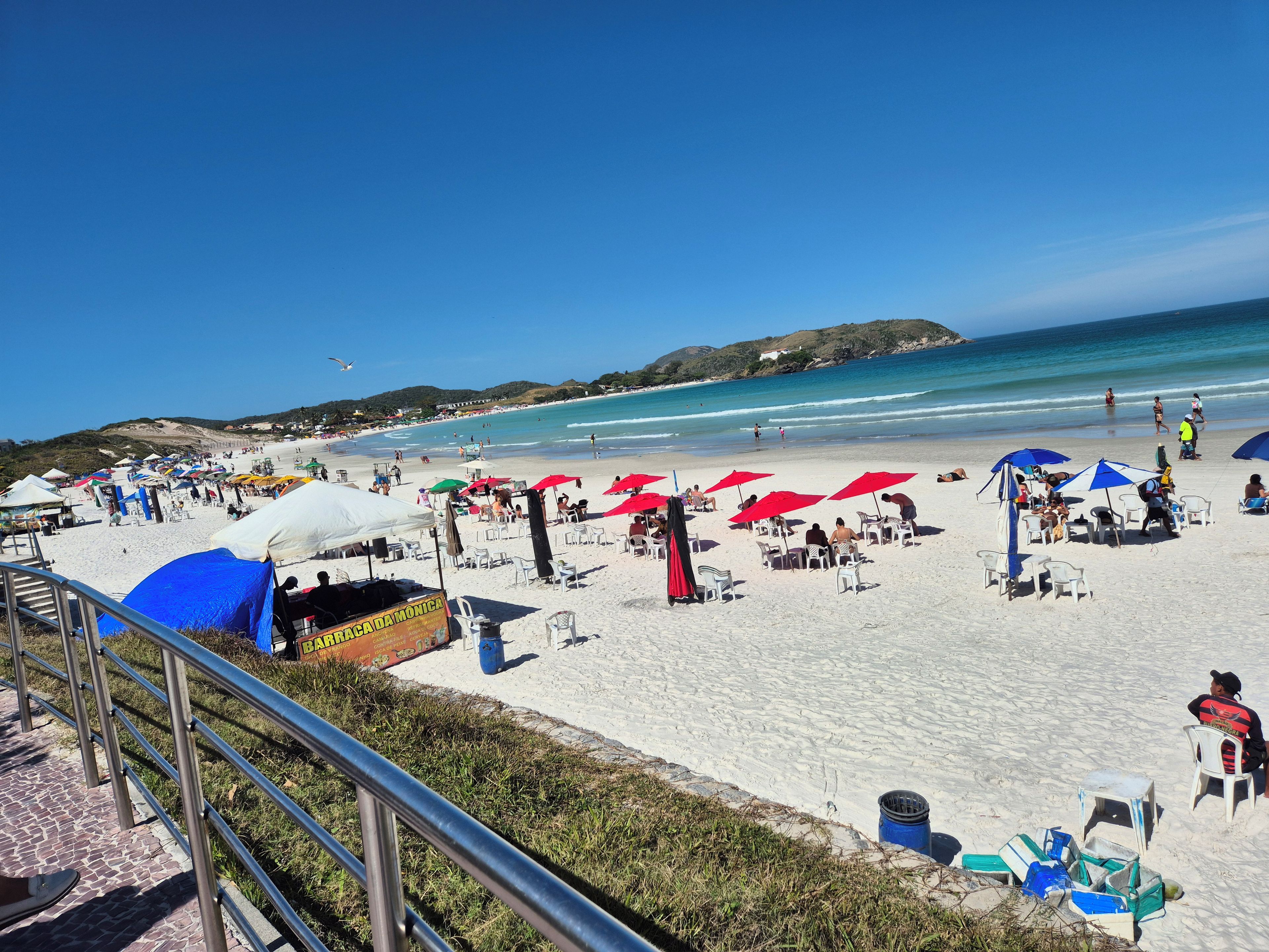 Una playa con sombrillas, sillas y un letrero de restaurante.