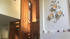 A wooden staircase leading to a loft bedroom, a fireplace with a fire, and a wall-mounted decorative piece.