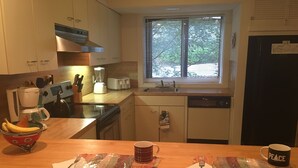 A kitchen with a wooden countertop, a window, and a refrigerator.