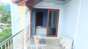 Ein Balkon mit Tisch und Stühlen, einem weißen Heizkörper und einer Tür zu einem Innenraum.