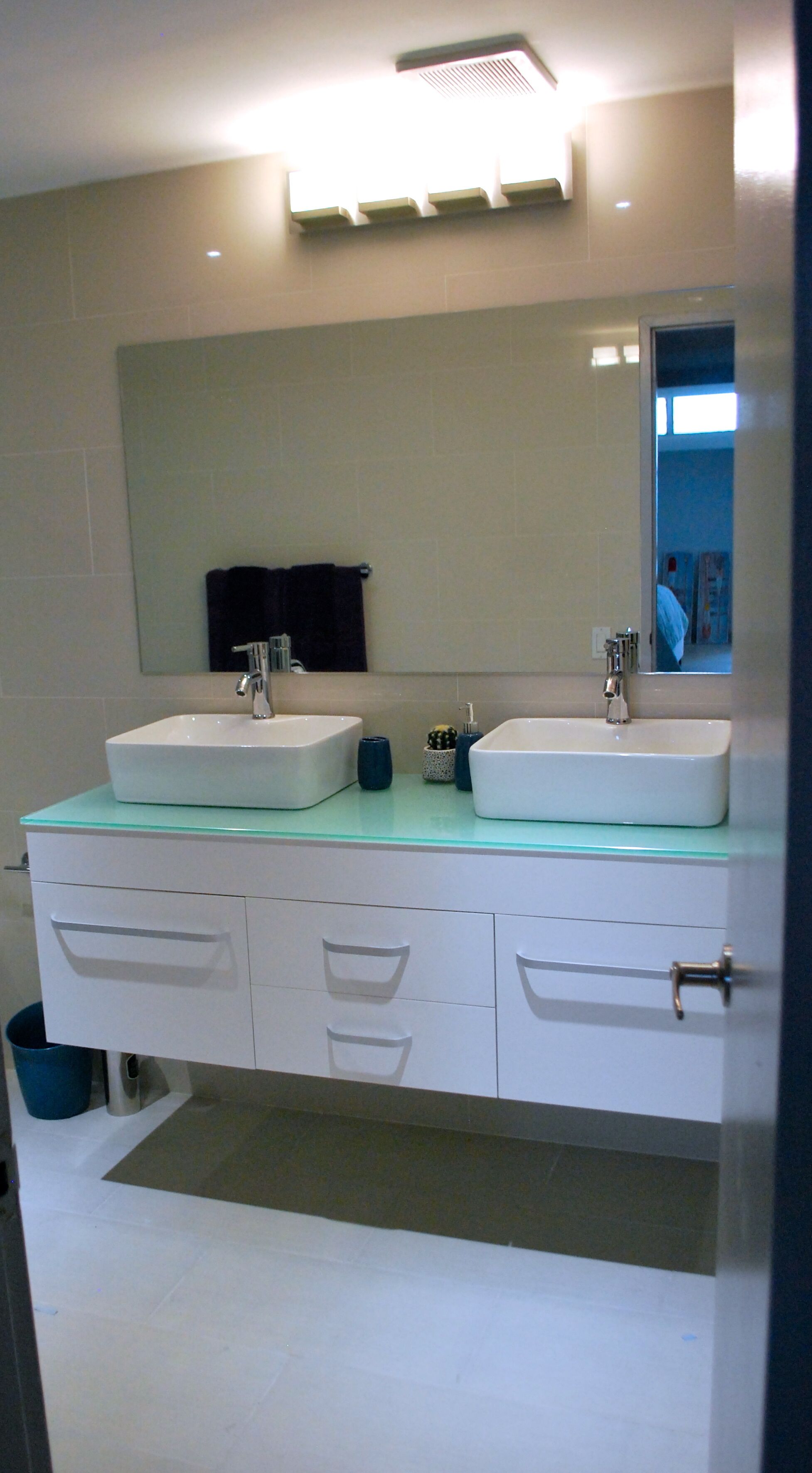Un baño moderno con dos lavamanos, un espejo grande y una encimera de vidrio.
