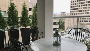 A round marble table with a metal lantern on it, surrounded by black metal chairs with patterned cushions. There are potted plants and a view of buildings in the background. - Bright and airy 2bed/2bath condo in the heart of downtown Victoria (Victoria)