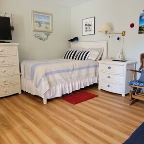Un dormitorio con cama, cómoda, mesita de noche, lámpara y decoración en la pared.