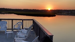 A deck with white chairs and a table, overlooking a calm body of water at sunset. - Beachy Condo! Cozy studio 3 minutes to Wells Beach (Wells)