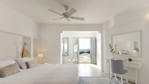 A modern bedroom with a bed, desk, and open door leading to a balcony. - Private pool, Breathtaking Panoramic View to the Sea & Sunset (Paros)