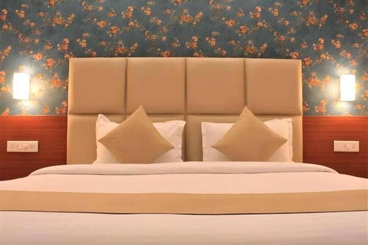 Una cama con cabecera, dos lámparas de noche y un fondo de papel tapiz floral.