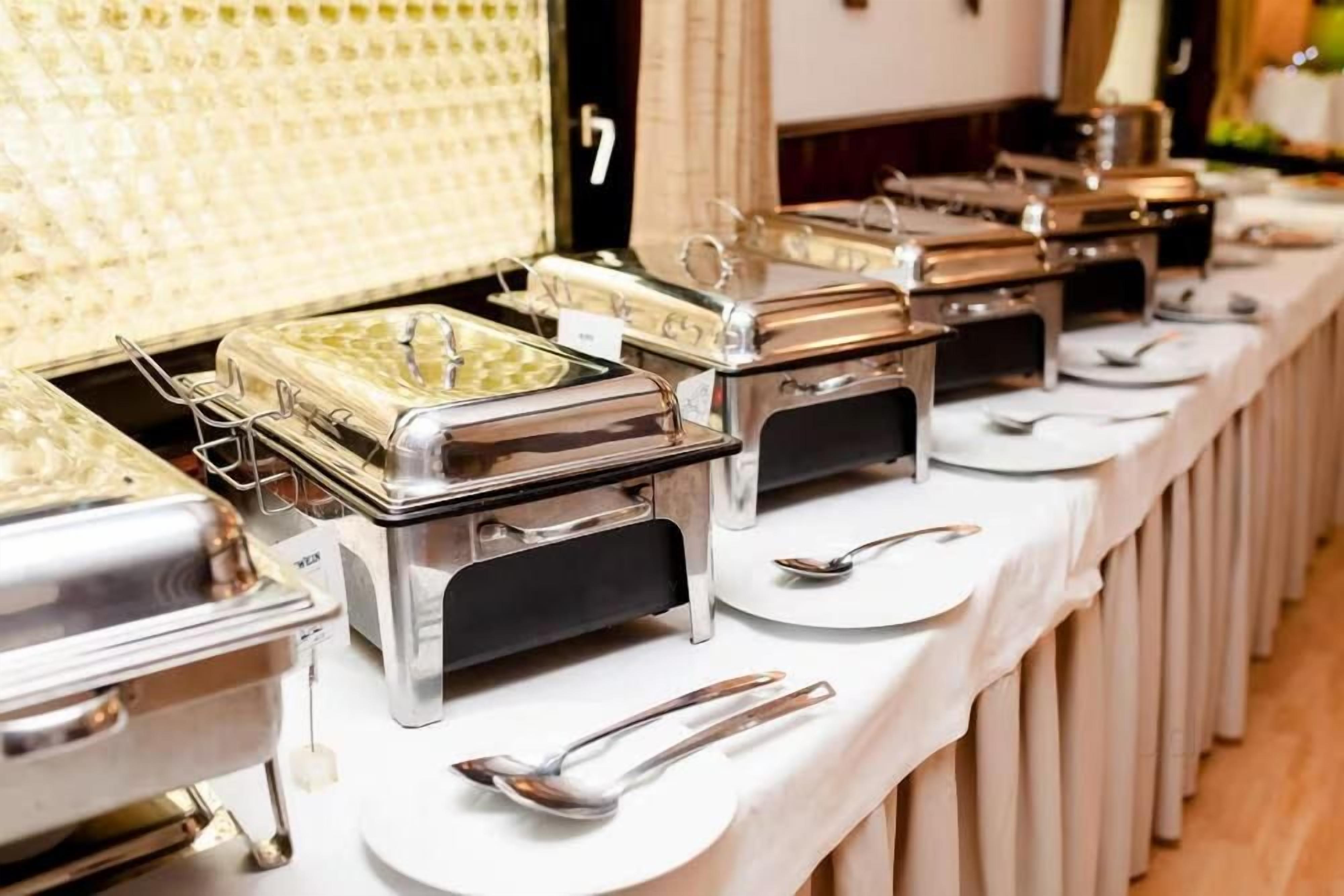 A buffet setup with multiple serving stations, each with a metal container and a spoon.