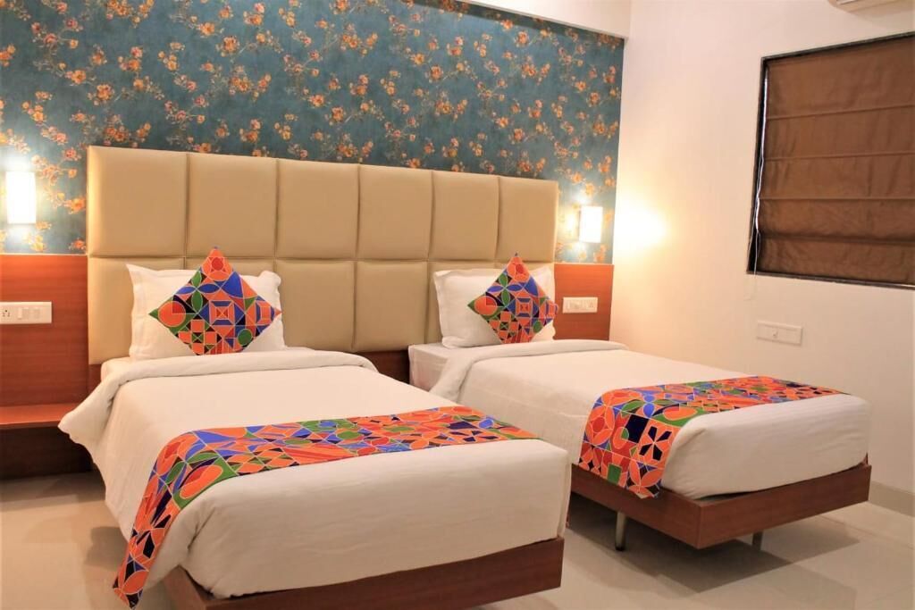 Una habitación de hotel con dos camas, papel tapiz floral y una ventana con persianas.