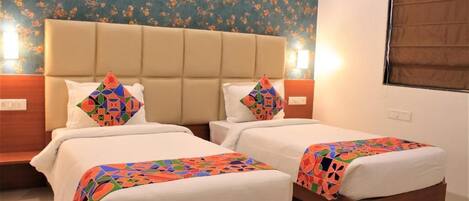 Una habitación de hotel con dos camas, papel tapiz floral y una ventana con persianas.
