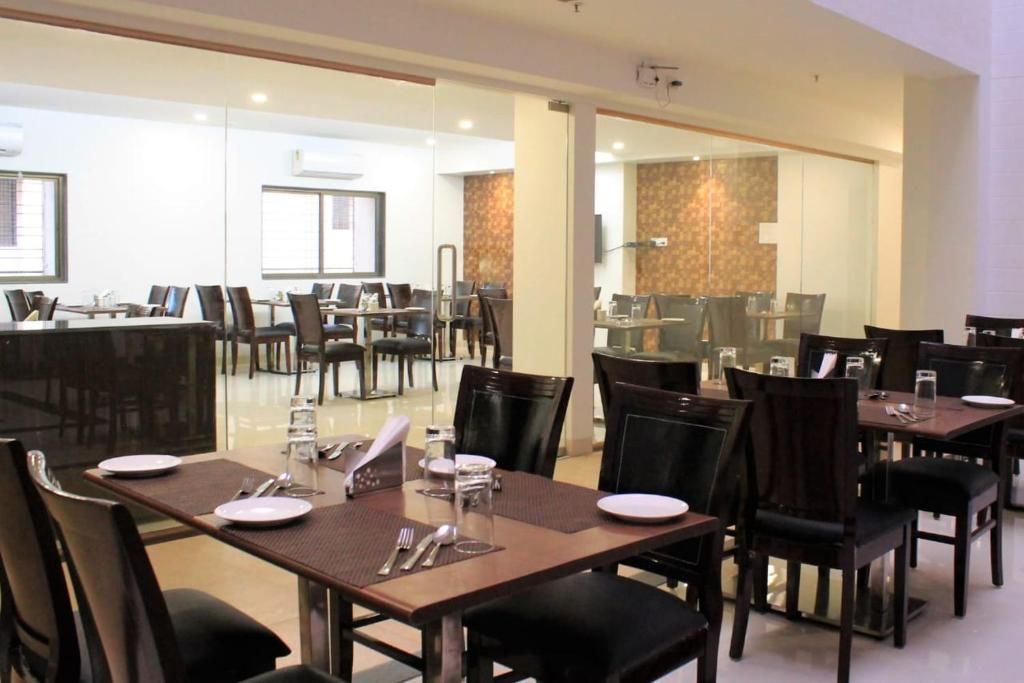 A restaurant with multiple tables and chairs, glass partitions, and a modern interior design.