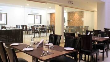 A restaurant with multiple tables and chairs, glass partitions, and a modern interior design.