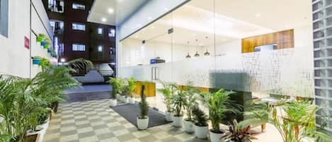 A hotel lobby with a checkered floor, potted plants, and a reception desk.