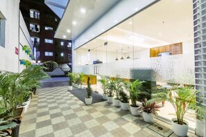 Un vestíbulo de hotel con piso de cuadros, plantas en macetas y un mostrador de recepción.