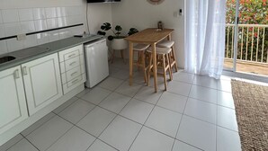 A modern kitchen with white cabinets, a built-in oven, and a flat-screen TV. - Surfrider | Bright Beachfront Apartment | Mollymook Beach (Mollymook Beach)