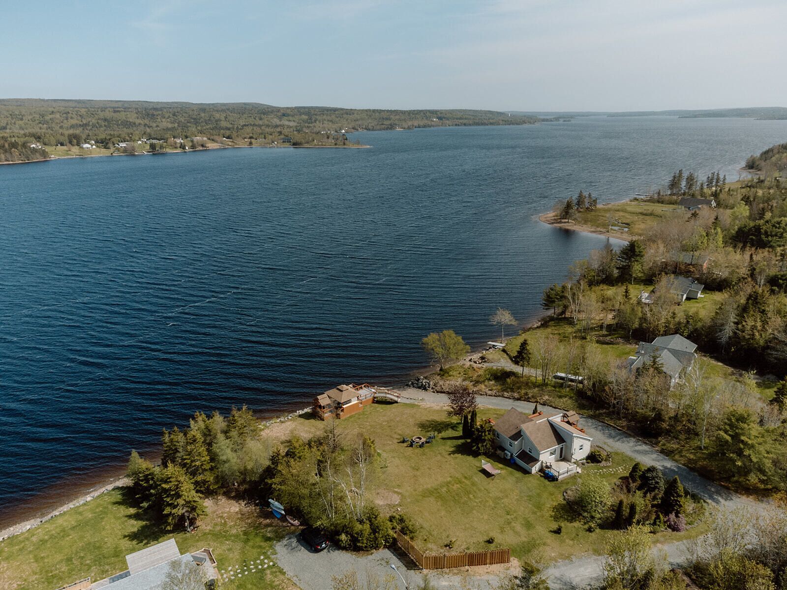 Une propriété au bord du lac comprenant une maison, un quai et un bateau.