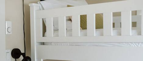 A bunk bed with white bedding and a single pillow.
