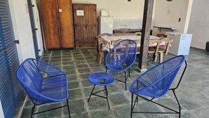 Une pièce avec un sol carrelé, une porte en bois, une table avec des chaises et un réfrigérateur.