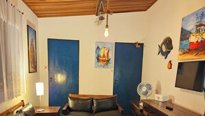 Un salon chaleureux avec un canapé en cuir, une table basse en bois et un téléviseur posé sur un meuble en bois.