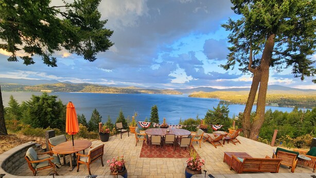 Un patio con mobiliario exterior, una bandera y vistas a un lago.