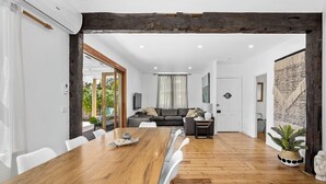A spacious living area with a wooden dining table, a sofa, and a large window.