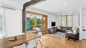 A modern living room with a sofa, TV, and dining area with chairs and a table.