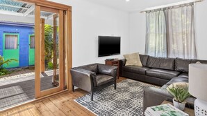 A modern living room with a leather sofa, a TV, and a wooden floor.